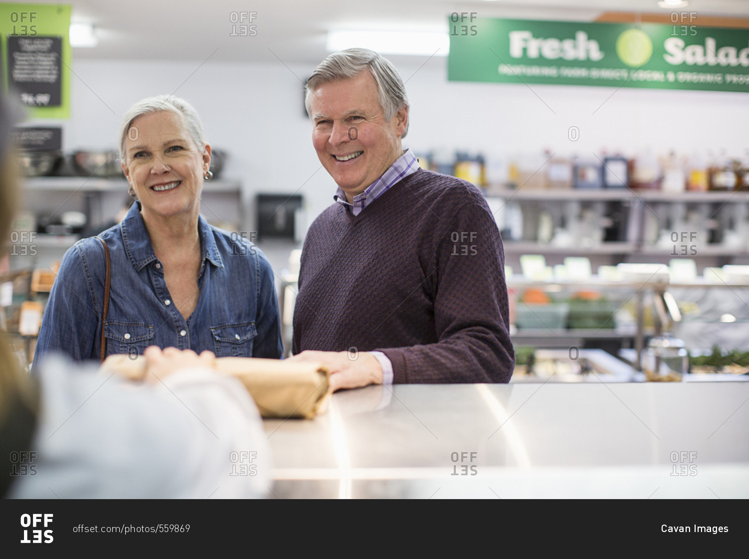 Cropped image of woman giving packet to senior couple at supermarket