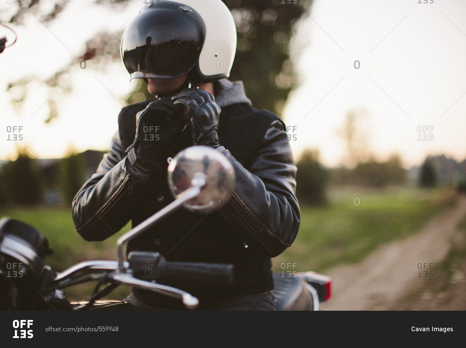 Male biker adjusting helmet while sitting on motorcycle