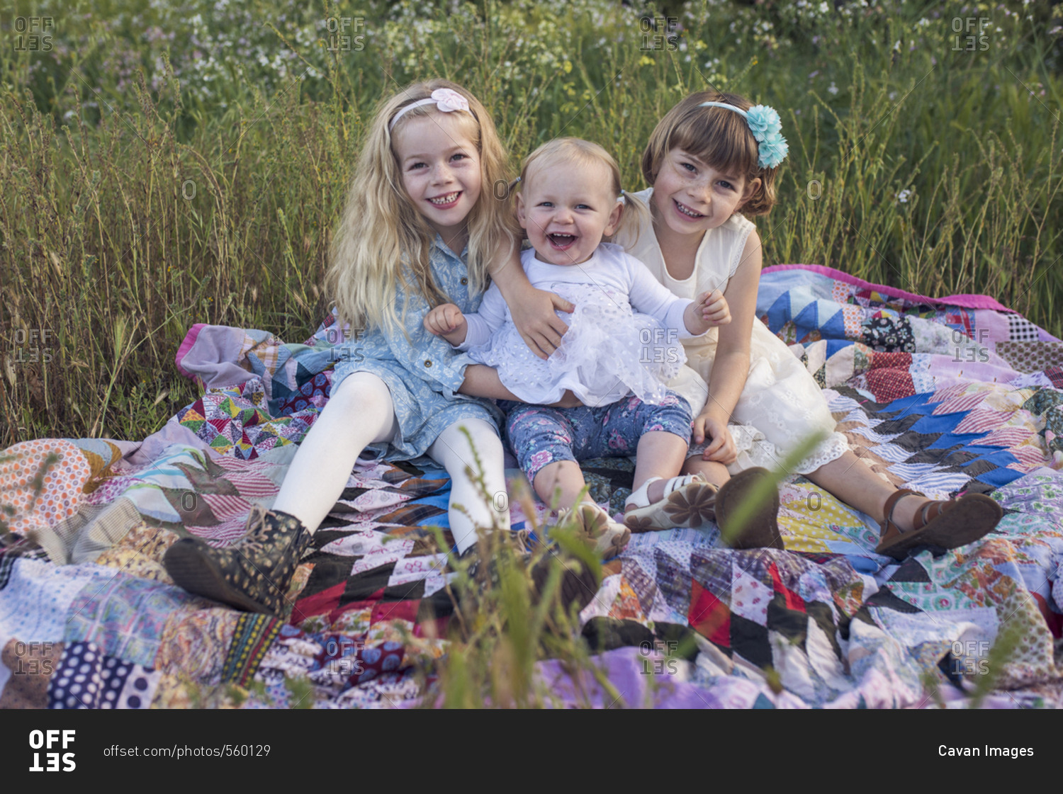 Portrait of happy sisters sitting on blanket in park