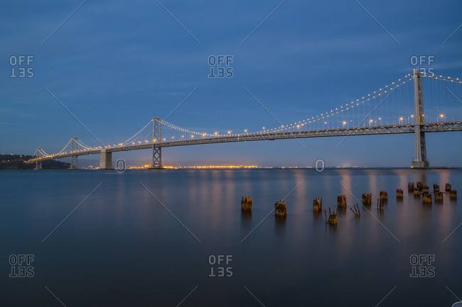 Illuminated Oakland Bay Bridge against blue sky at dusk