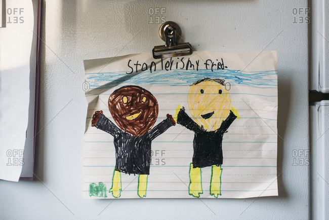 Child's drawing of African American and Caucasian friends hung on a refrigerator with a magnet
