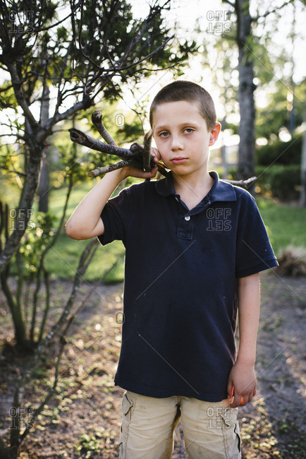 Boy holding sticks over his shoulder and making a serious expression