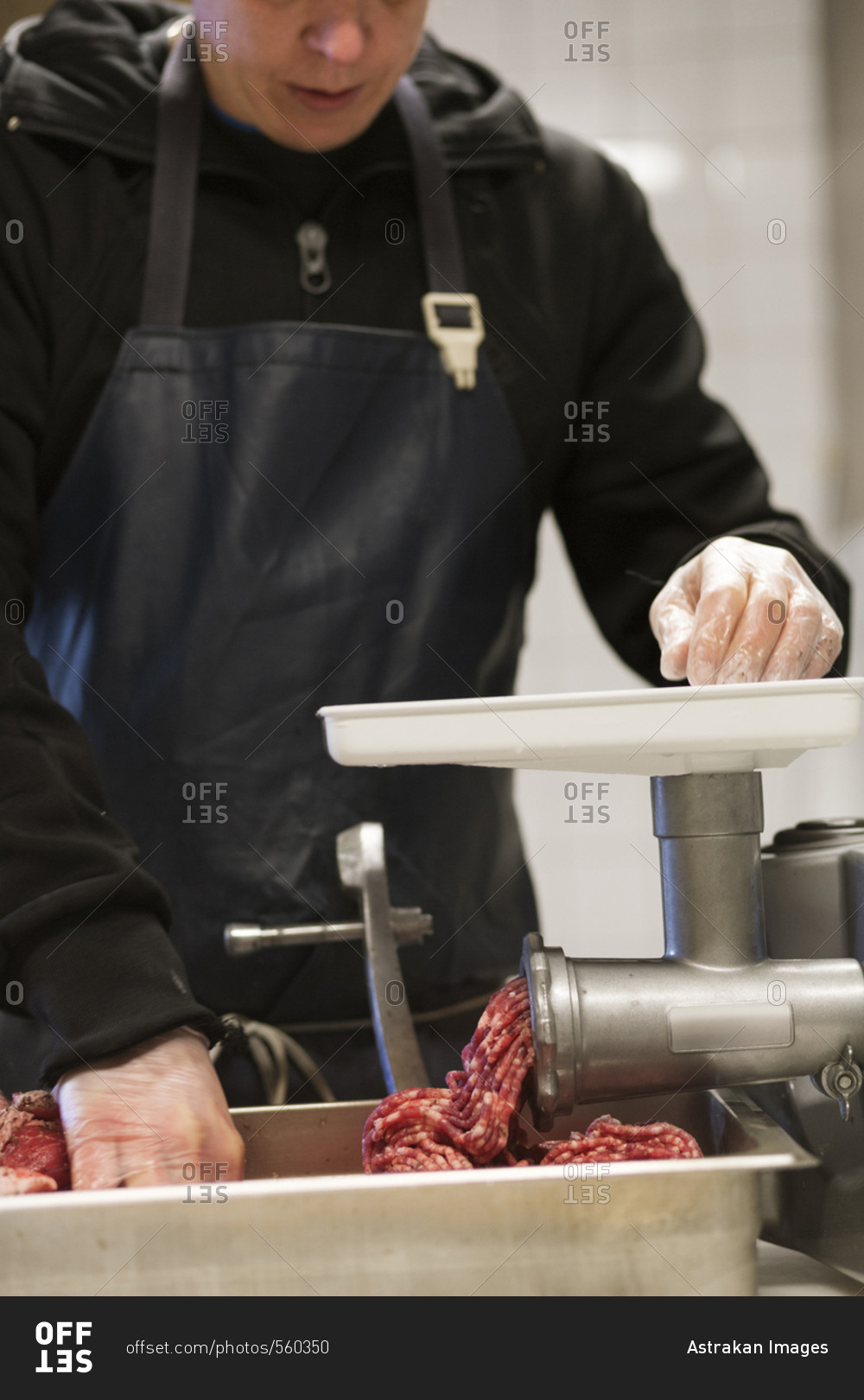 Mid section of man grinding meat to make pork sausages
