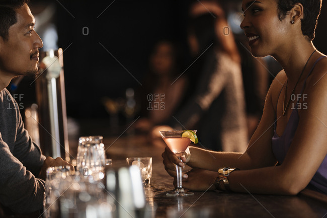 Happy woman talking to male bartender at bar counter in nightclub