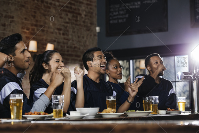 Happy sports fans watching TV at bar in pub