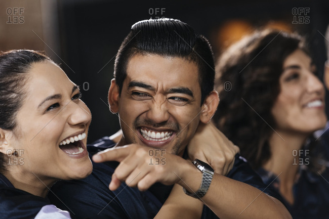 Happy mid adult woman embracing man while watching soccer match in bar