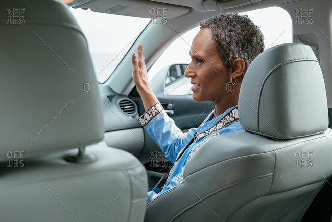 Side view of mature woman gesturing while sitting on front seat of car