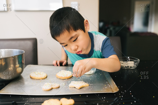 Boy Putting Sprinkles On Sugar Cookies Stock Photo Offset