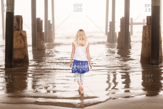 Girl walking under pier at Galveston, Texas