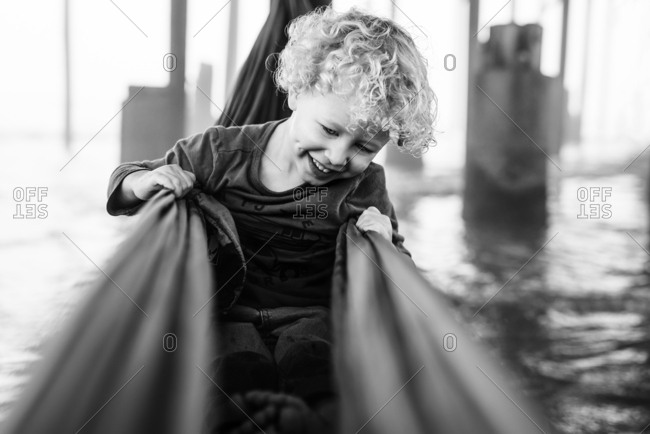 Boy in hammock under pier in Galveston, Texas in black and white