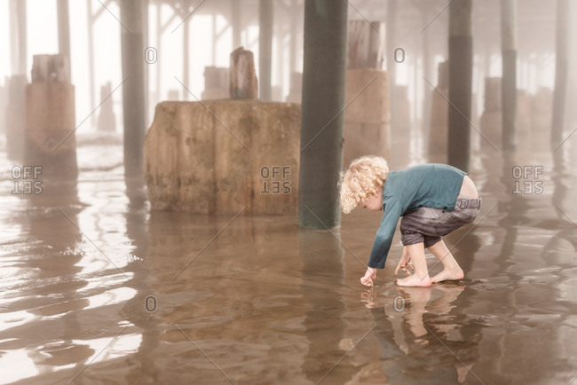 Little boy playing under pier in Galveston, Texas