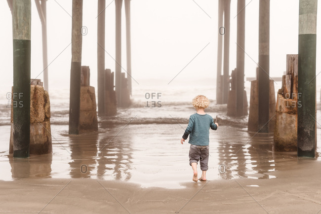 Little boy walking under pier in Galveston, Texas