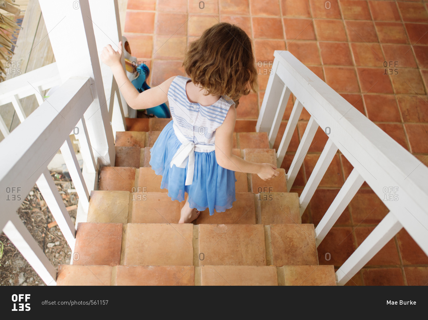 little-girl-walking-down-stairs-leading-to-patio-stock-photo-offset