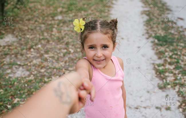 Girl with flower in her hair holding hand of parent