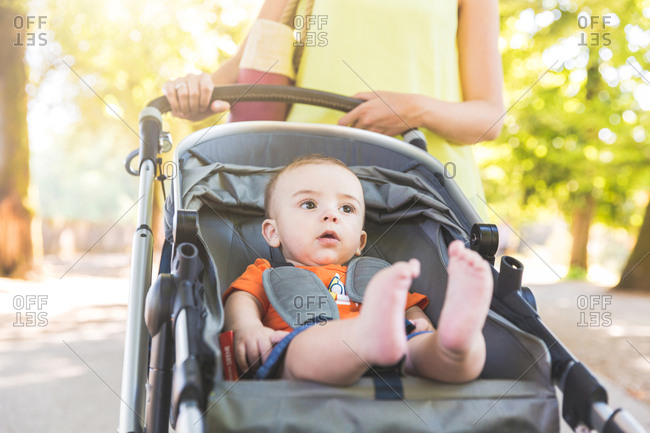Mother pushing baby boy in stroller, mid section