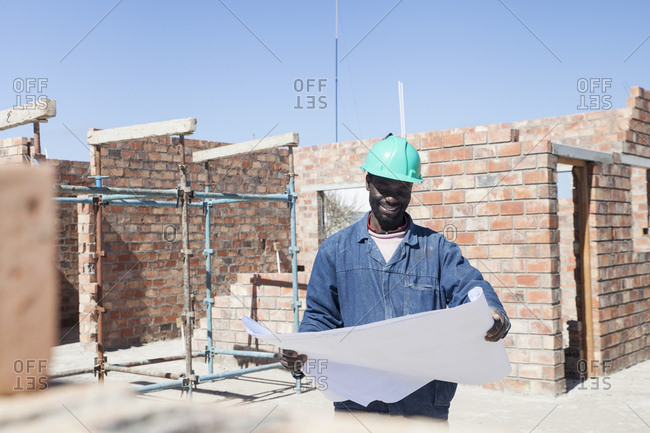 Builder looking at blueprint on construction site