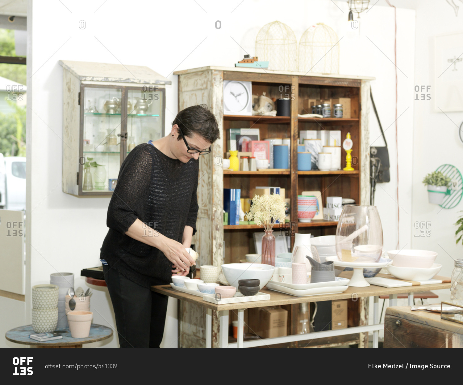 Mature female shop keeper preparing table display in gift shop