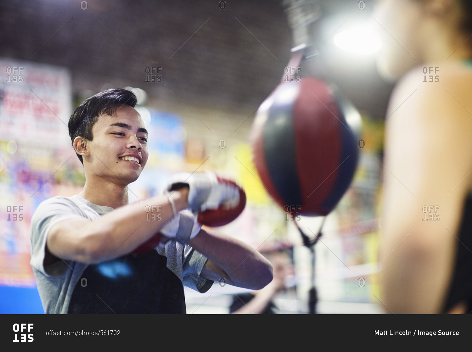 Young male boxer punching speed bag in gym