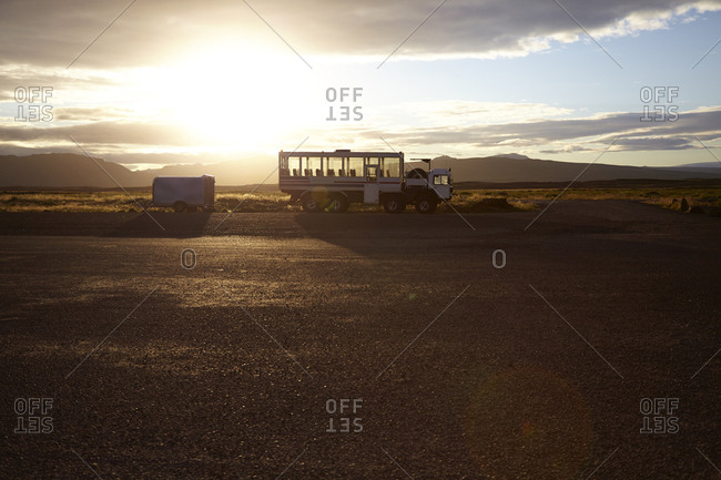 Tourist truck parked in landscape with distant mountains at sunrise, Iceland