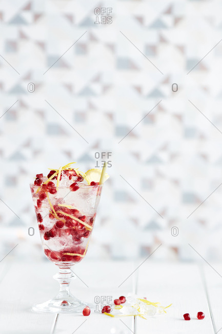 Non-alcoholic cocktail in glass with lemon rind and pomegranate