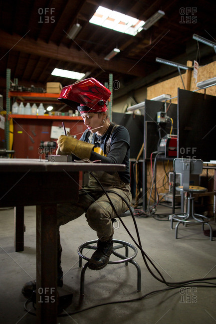 Female metalsmith preparing metal rods at workshop bench