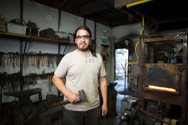 Portrait of male metalsmith by metal workshop furnace