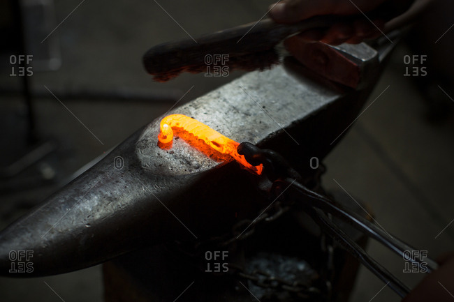 Red hot metal rod on metal workshop anvil