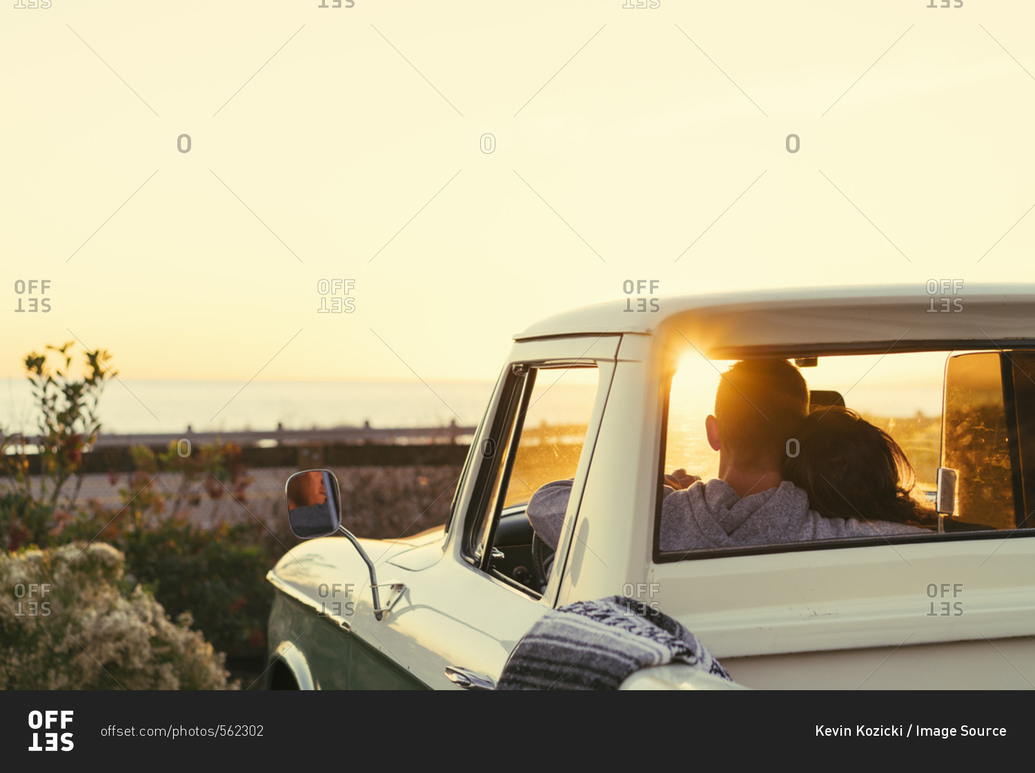 Rear view of couple in pickup truck watching sunset at Newport Beach, California, USA