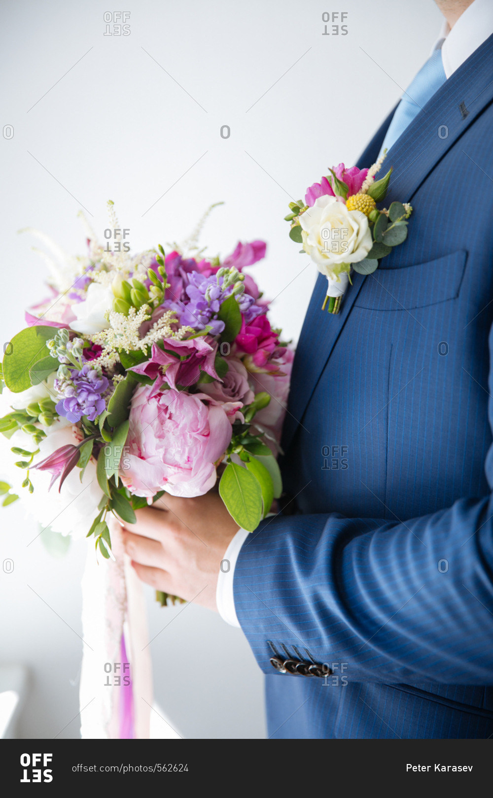 Groom holding a bouquet of purple and pink flowers