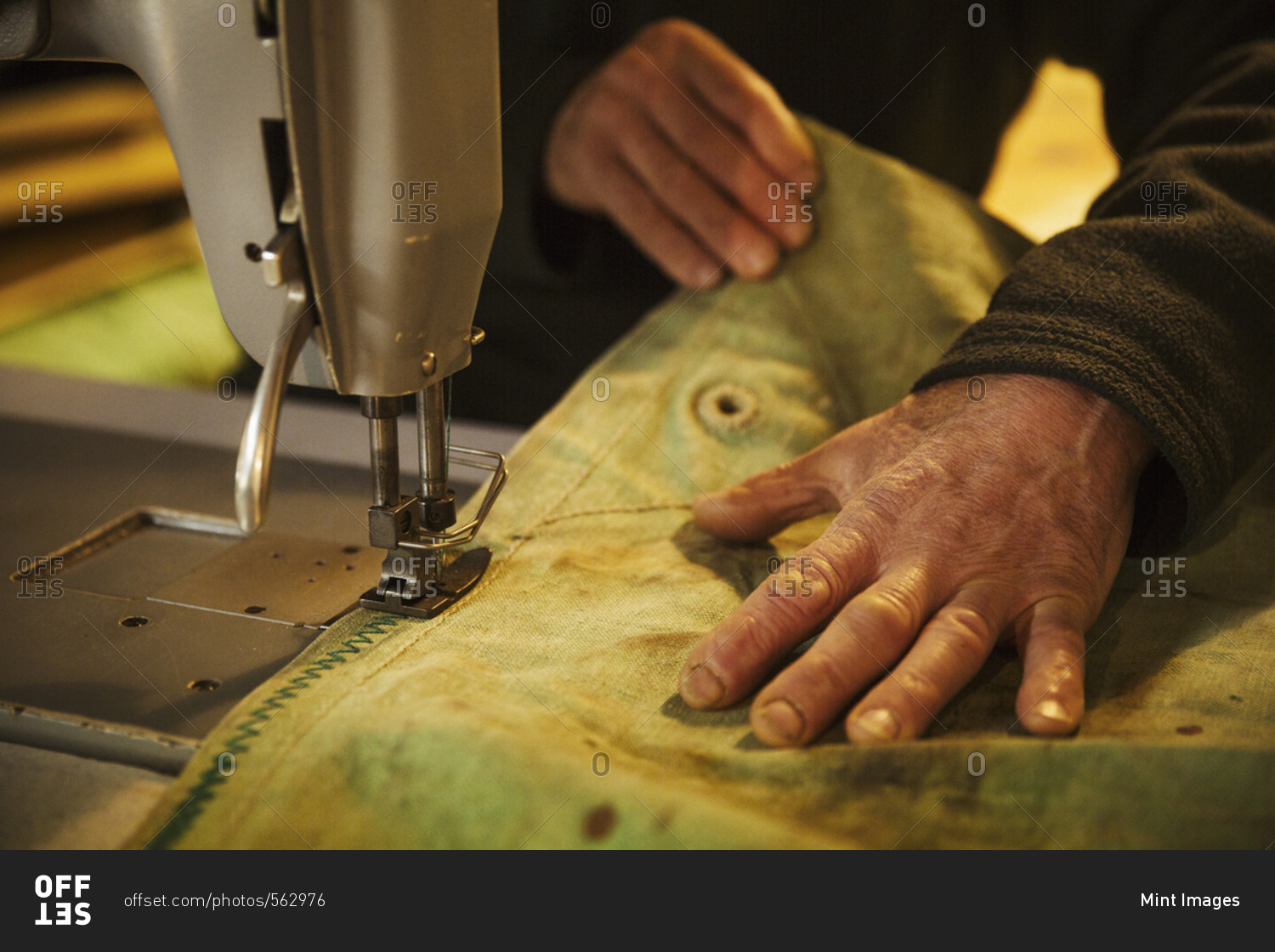 Close up of a man in a sailmaker's sewing a sail with a sewing
