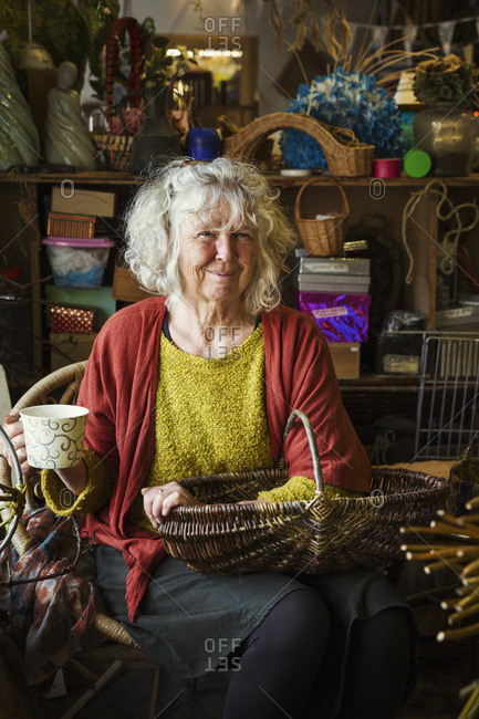Woman sitting in a basket weaver's workshop, holding a basket.