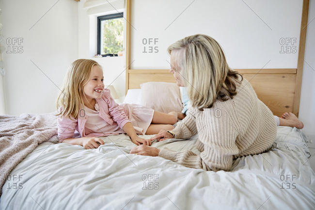 Little Girl Lying On The Bed With Her Grandmother Having Fun