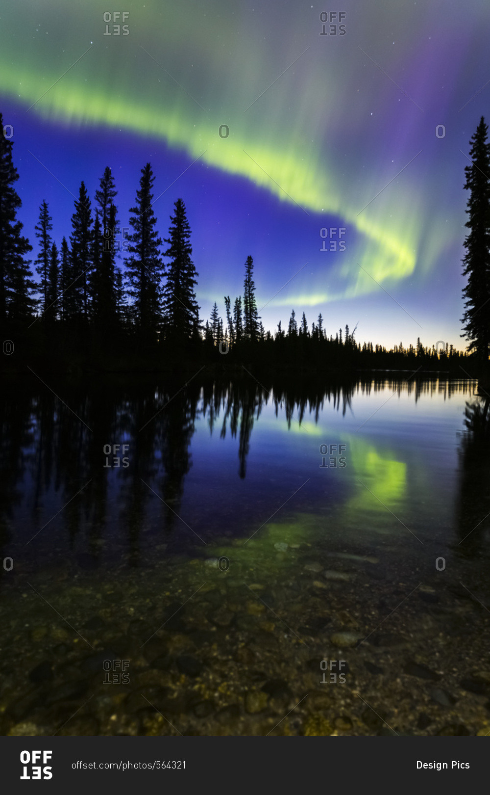 The aurora borealis reflects in the Clearwater River in Delta Junction shortly before sunrise, Alaska, United States of America