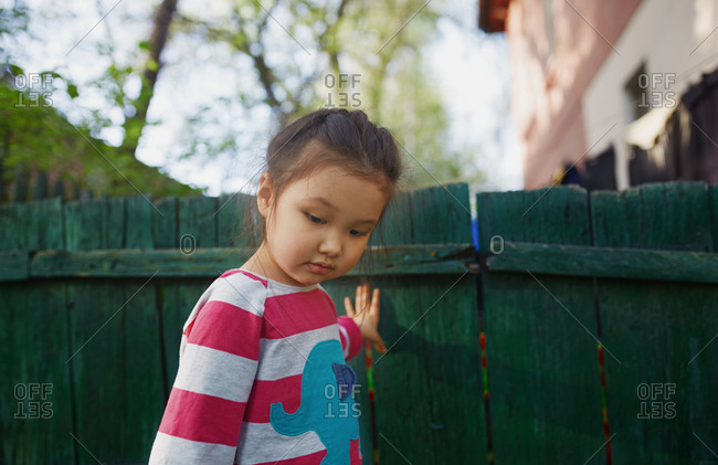 Cute girl standing at the wooden fence