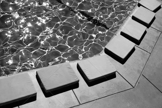 Rectangular cushions lining the edge of a poolside