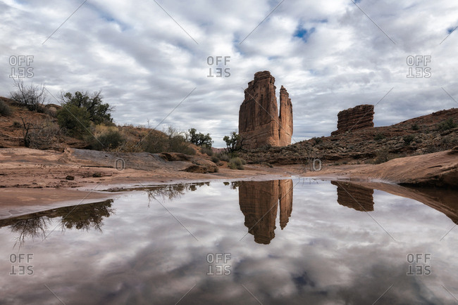 Reflection of rock formation and clouds in puddle