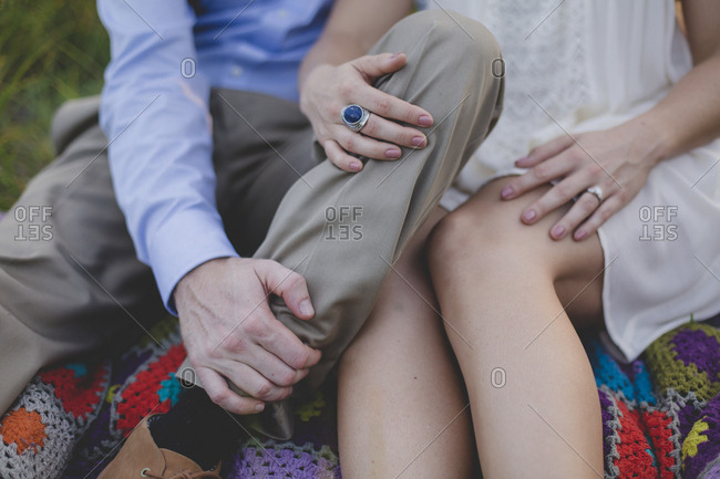 Couple sitting next to each other on a blanket in a field