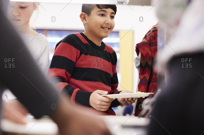 Boy holding plate in lunch line at school cafeteria