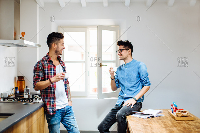 Male couple relaxing in kitchen, drinking coffee
