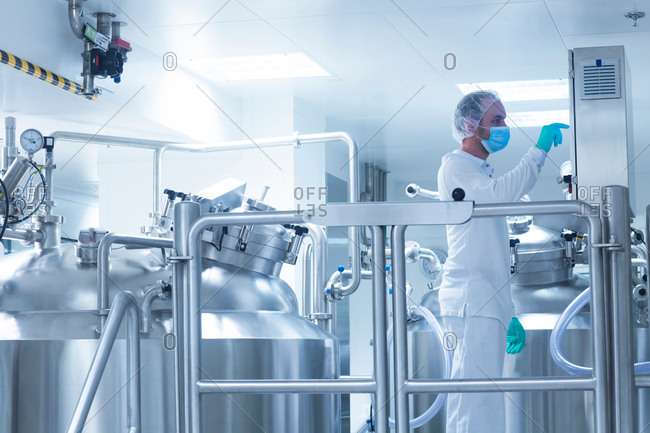 Worker operating pharmaceutical production equipment in pharmaceutical plant