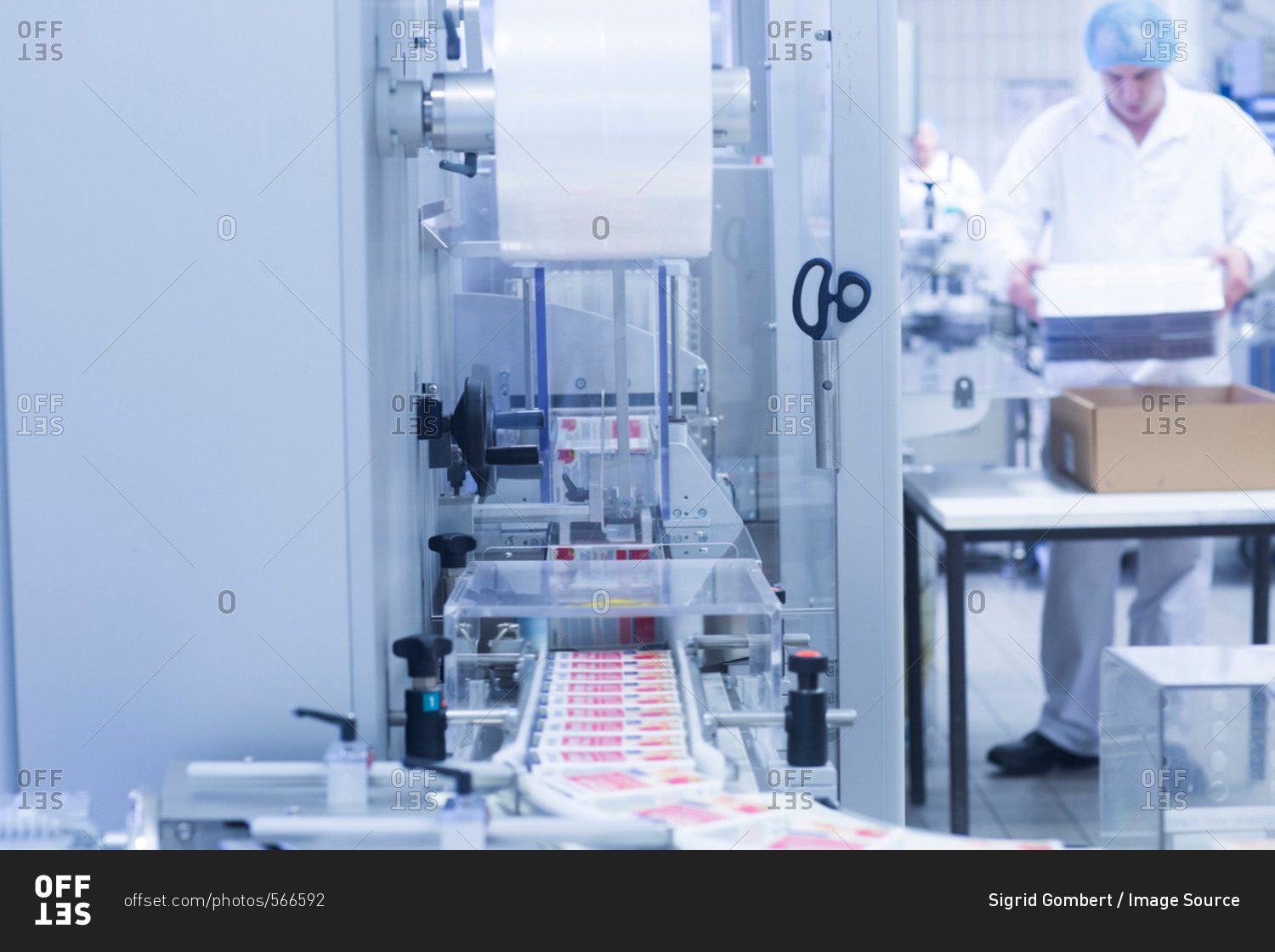 Workers packaging pharmaceutical products on production line in pharmaceutical plant