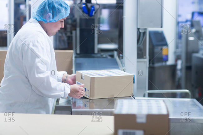 Worker packaging pharmaceutical products in pharmaceutical plant