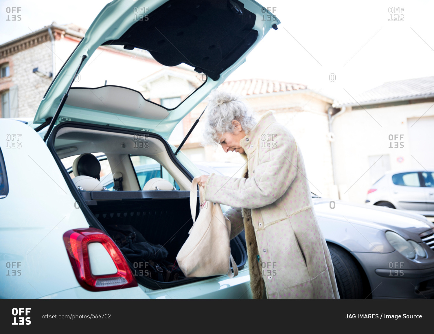 Mature woman with shopping bag looking in car trunk