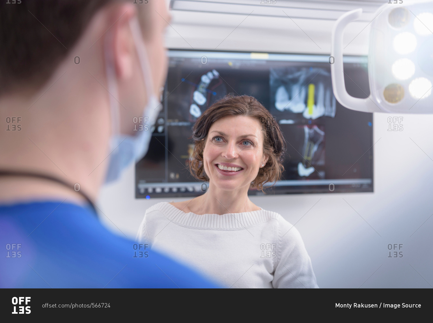 Dentist showing x-rays on screen to patient in dental surgery