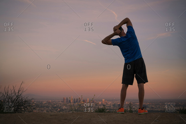 Rear view of jogger stretching at dusk, Runyon Canyon, Los Angeles, California, USA