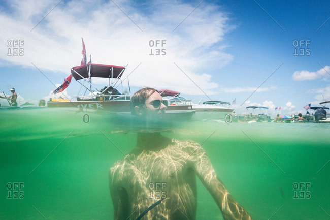 Split water level surface image of teenage boy in water, Crab Island, Emerald Coast, Gulf of Mexico, USA