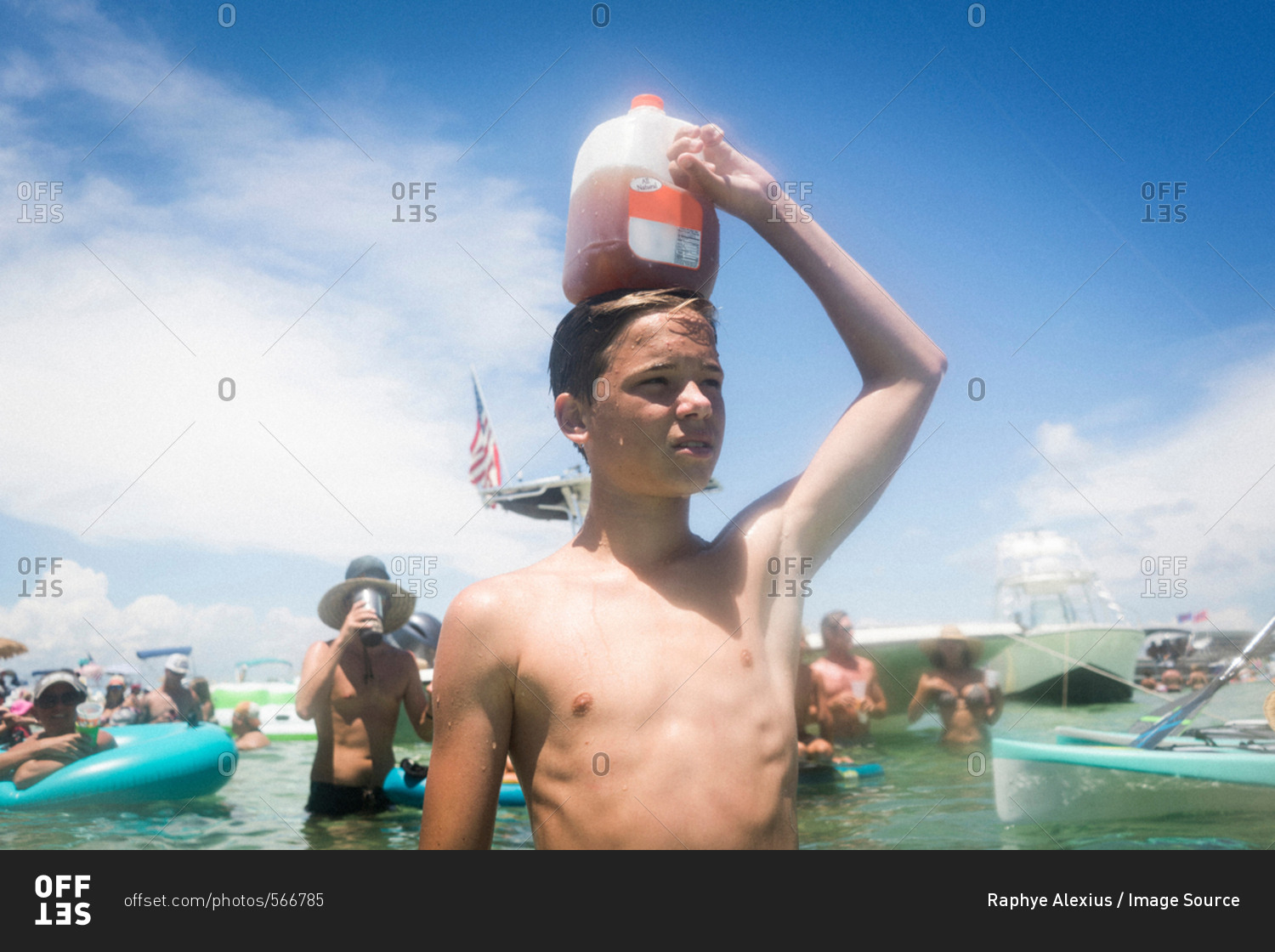 Teenage boy in water holding juice carton on head, Crab Island, Emerald Coast, Gulf of Mexico, USA