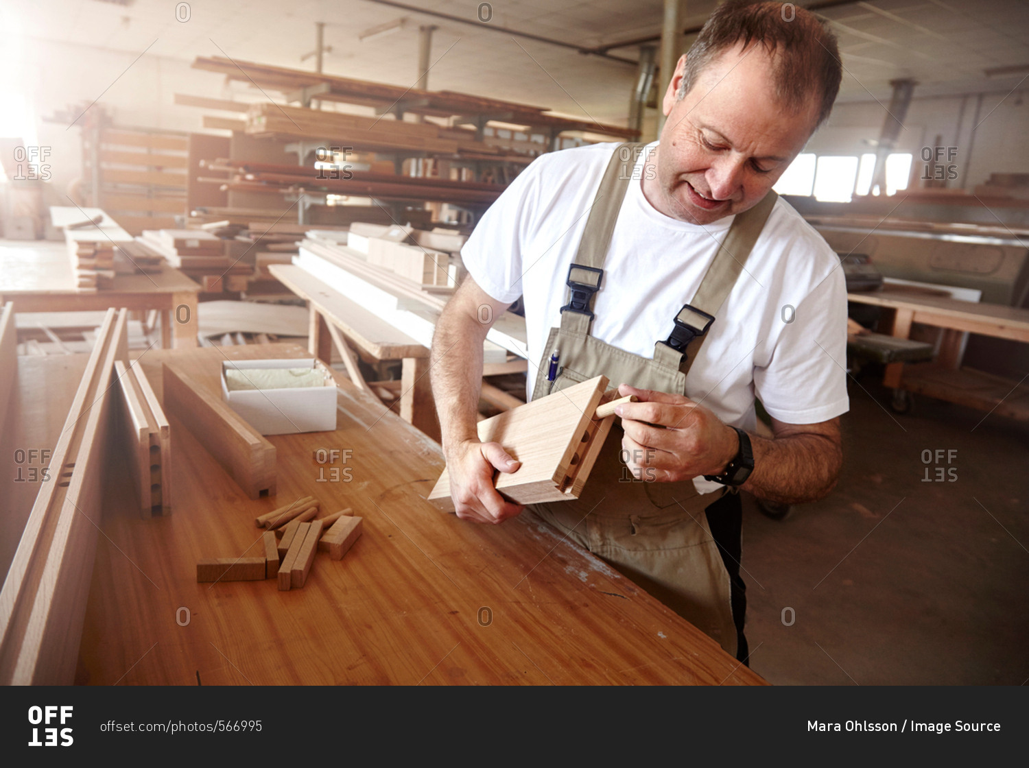 Male carpenter inserting wooden dowel at workbench