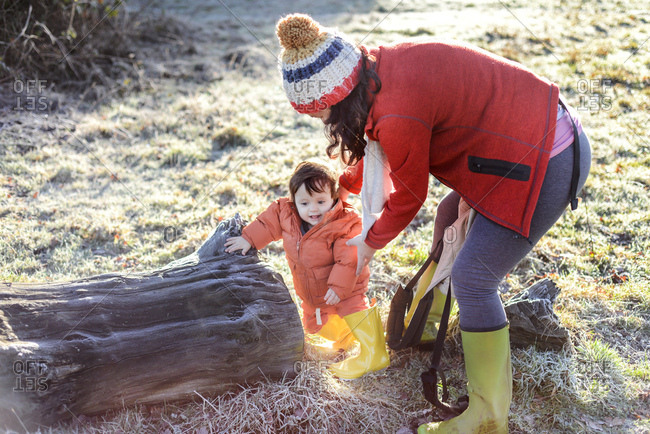 Mother steadying baby boy, outdoors, in winter