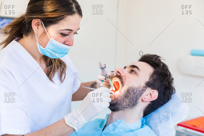 Female dentist giving male patient anesthetic injection
